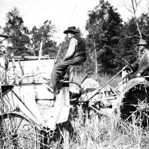 White farmer in cowboy hat and vest driving a harvester