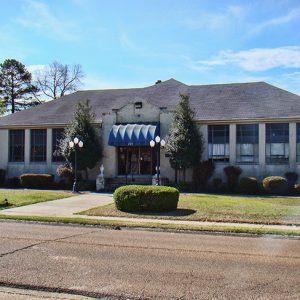 Single-story building with blue awning and sign on street