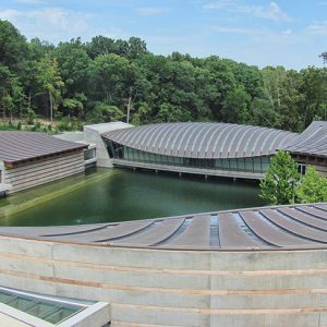 Reflecting pool in between modern buildings with rounded roofs and trees in background