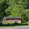 Single-story house and red barn with "Crystal Springs" written on its side next to two-lane highway