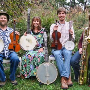 Two white men and two white women sitting outside with banjos fiddles and saxophone