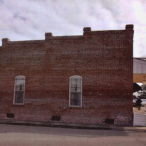 Side view of brick storefront with covered entrance and balcony