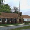 Single-story building with arched stone entry way and tall spire