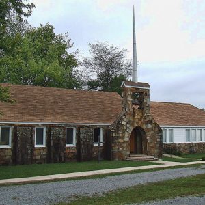 Single-story building with arched stone entry way and tall spire