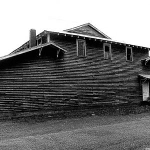 Side view of gymnasium building with elevated windows and door under awning and garage door