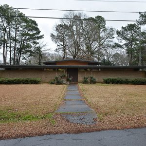 Brick building with flat roof with sidewalk and front yard