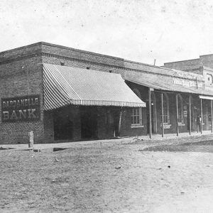 Single and multistory buildings with awnings on dirt street