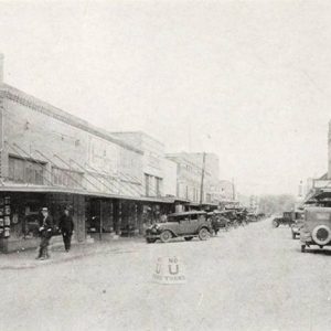 Looking down town street with parked cars and multistory buildings on both sides