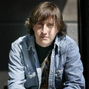 Young white man sitting in long sleeved denim shirt