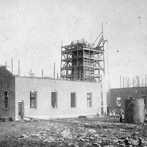 Brick building under construction with scaffolding on tower