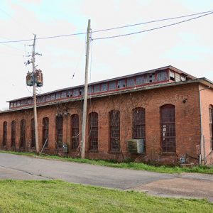 Brick building with tall arched windows and power lines on street