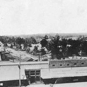 Looking over brick storefront buildings with awnings to residential street in the background