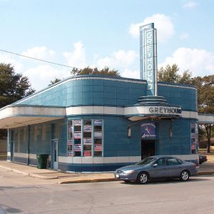 Car parked in front of blue and white building with "Greyhound" signs