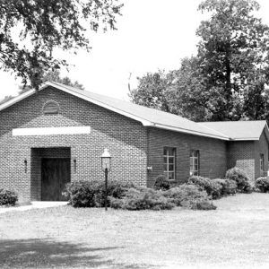 Single-story brick building with bushes