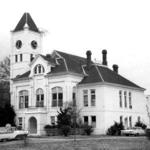 Three-story white brick building with arched entrance and clock tower