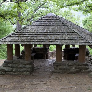 Stone and wood pavilion surrounded by trees