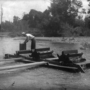 Worker sifting for diamonds while standing on machinery in water