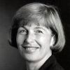 White woman with short hair smiling in suit