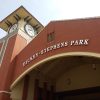 Looking up at brick clock tower and arched entrance way to baseball stadium with hanging light fixtures