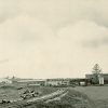 Multistory buildings with four smokestacks and train tracks in the foreground