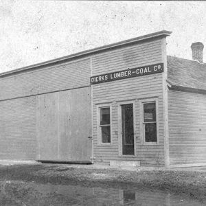 Single-story storefront building with storage building on dirt street