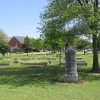 Engraved stone monument in field with planters and trees