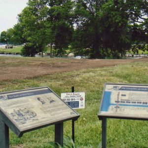 Field and lake with flat interpretation panels and trees