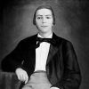 Young white man sitting down in suit and bow tie