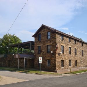 Three-story stone building with modern elevated balcony area on street corner