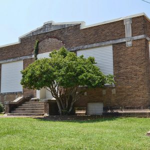 Brick building with covered windows and tree in front