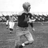 Young white man in uniform and helmet running with football