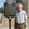 Older white man with glasses standing next to "Statistical Avian Ecology" sign outside school building