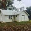 Single-story building with cupola and white siding on grass