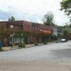 Brick storefronts and trees on street with flags