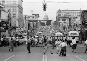 busy city intersection with cars and people, view of state capitol in background