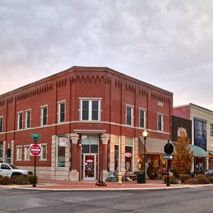 Multistory storefront buildings with illuminated street lamps on town street