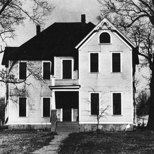 Two-story house with trees and sidewalk