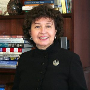 white woman holding glasses in front of book shelf