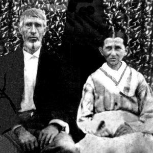 Old white man in suit standing with old white woman in dress