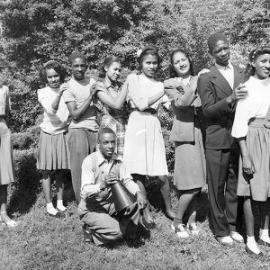 African-American boys and girls posing outside brick building