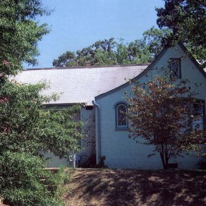 Brick house with curved roof and arched windows behind trees