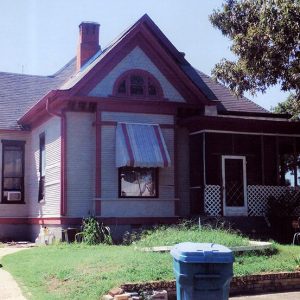 House with screened-in porch between parked cars and tree