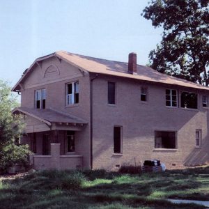 Multistory brick house with covered porch and brick chimney