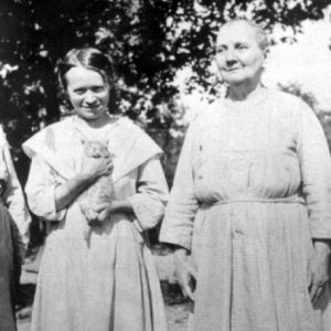 Young white woman in dress holding a kitten posing with older white woman