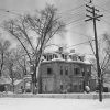 ornate multistory house inside fence with trees and snow covered yard