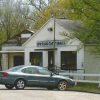 Car parked in front of single-story building next to brick storefront with awning