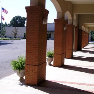 Covered sidewalk with brick columns arches and driveway flag pole U.S. and Arkansas flags