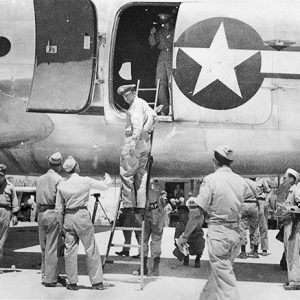 Young soldiers talking to white officer using ladder to get on large airplane