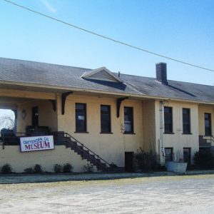 Yellow depot building with covered porch area and parking lot