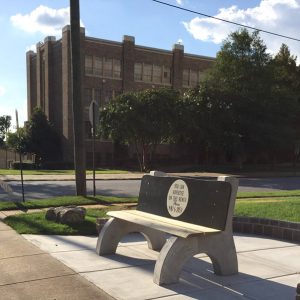 Bench across the street from multistory brick building